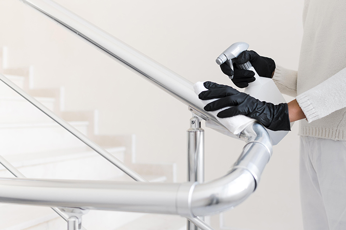 hands-with-gloves-disinfecting-hand-rail